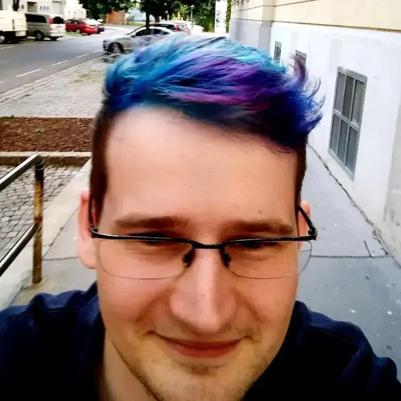 A portrait of Thomas with colorful hair